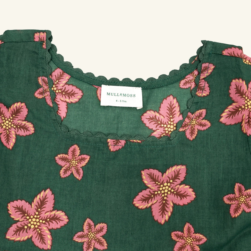 Green fabric with pink floral patterns and a visible label on a white background